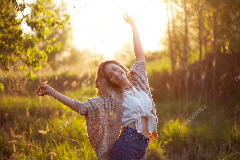 Cute charming girl in summer in the field. Young woman is happy and feels free outdoors