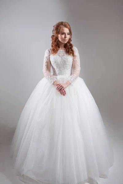 Mooie jonge vrouw bruid in weelderige trouwjurk. Lichte achtergrond. — Stockfoto