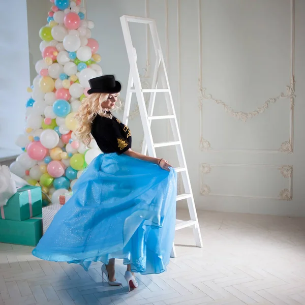 Leuke en mooie blonde dansen in een prachtig interieur. Charmante jongedame in een bochtige blauwe rok. — Stockfoto