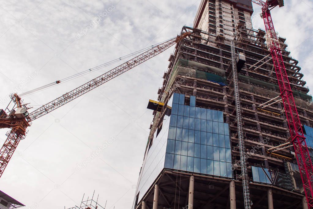 Construction of high-rise building. Construction cranes and skyscraper 