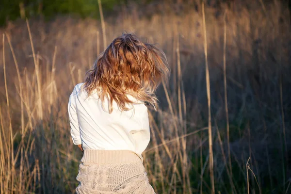 Милая очаровательная девушка летом в поле. Молодая женщина счастлива и чувствует себя свободно на открытом воздухе. Вид сзади — стоковое фото