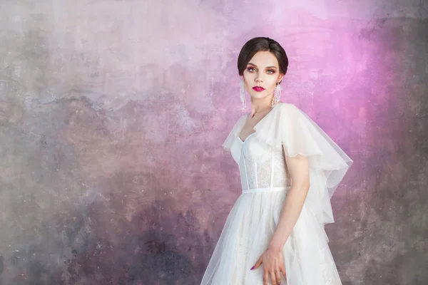 Mooie en stijlvolle bruid in trouwjurk in Studio op grijs gestructureerde achtergrond — Stockfoto