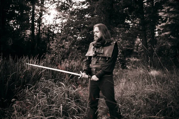 Cavaliere nella foresta. Ragazzo in costume medievale con spada . — Foto Stock