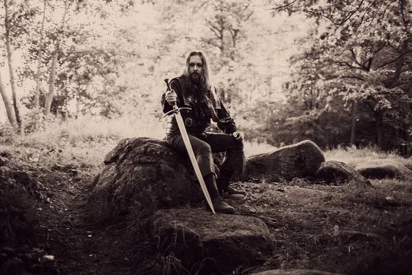 Ritter im Wald. Mann im mittelalterlichen Kostüm mit Schwert. Wirkung der Straffung — Stockfoto