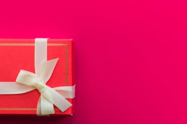 Parlak kırmızı zemin üzerine kırmızı hediye kutusu. Sevgi ve hediyeler.