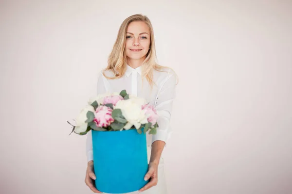 Elegant blomma leverans, gåva. Kvinna med blommor i en hatt-låda. Bukett av pioner. — Stockfoto