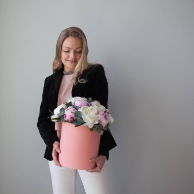Sevimli sarışın kadın bir şapka kutusunda çiçekli. Peonies buket.