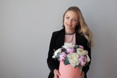 Sevimli sarışın kadın bir şapka kutusunda çiçekli. Peonies buket.