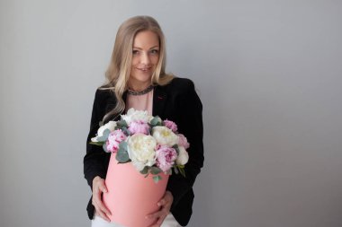 Sevimli sarışın kadın bir şapka kutusunda çiçekli. Peonies buket.