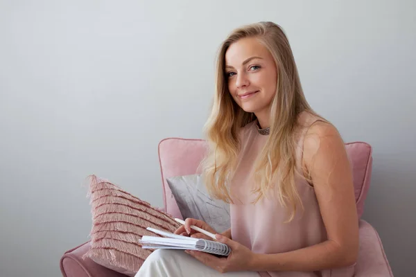 Jonge vriendelijke vrouw zittend in een stoel met een laptop in haar handen. Een leuke metgezel. — Stockfoto