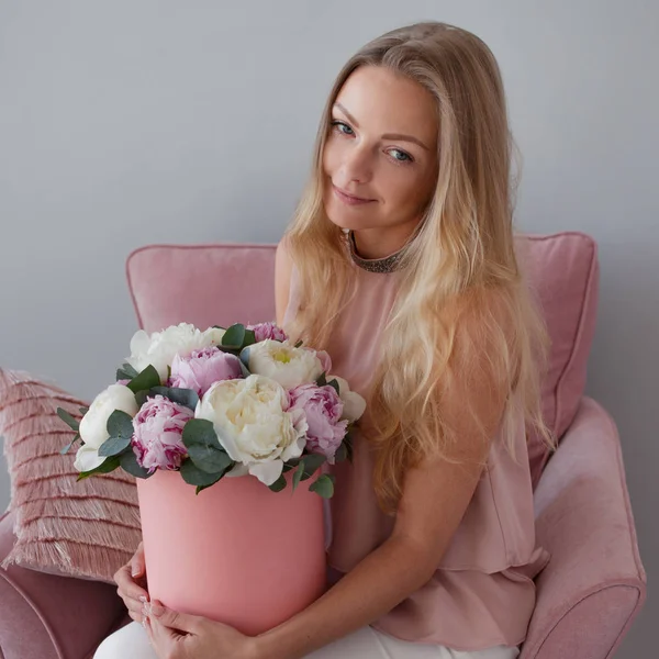 Happy blonde woman with flowers in a hat box. Bouquet of peonies. — Stock Photo, Image