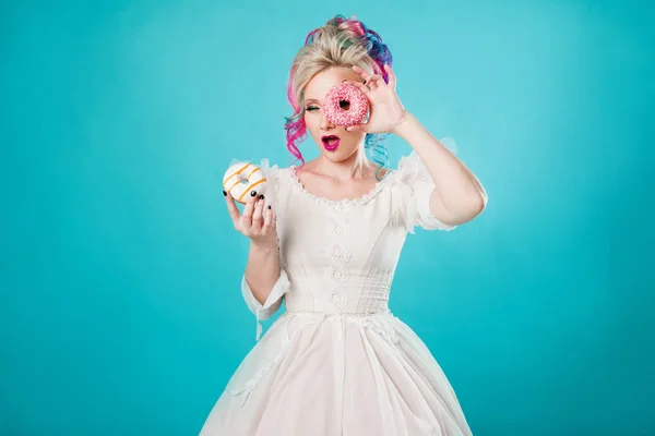 Mulher nova fresca com cabelo colorido. Segura dois donuts doces, engraçado — Fotografia de Stock