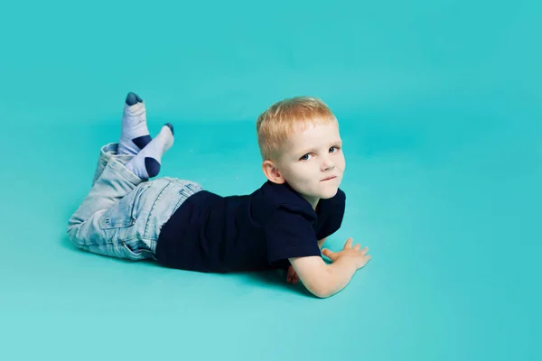 Retrato de un niño pequeño. Acostado sobre fondo azul — Foto de Stock