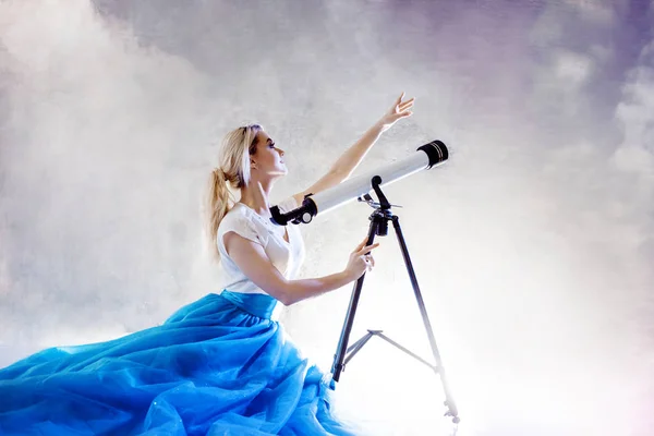 Νεαρή γυναίκα ονειρεύεται το μέλλον, έννοια. Κορίτσι στον ουρανό με σύννεφα αναζητά και χρησιμοποιεί ένα τηλεσκόπιο. — Φωτογραφία Αρχείου