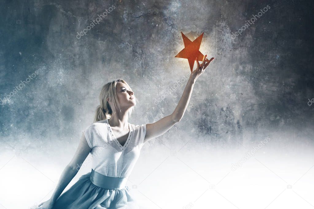 Young attractive woman reaching for the star. Take a star from the sky, dreams and plans, concept