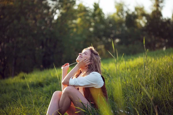 Счастливая женщина в белой рубашке наслаждается пикником на природе. Девушка сидит на траве, отдыхает, отдыхает — стоковое фото