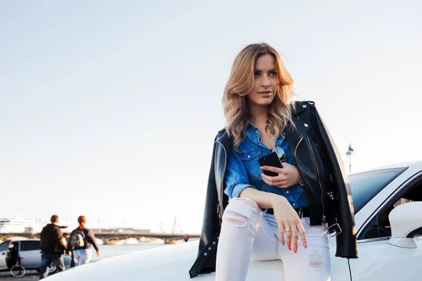 Mulher loira jovem bonita e elegante. Retrato com telefone no fundo de seu carro — Fotografia de Stock