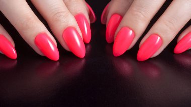 Kadınların elleri ile mükemmel kırmızı manikür. Oje kırmızı mercan rengi. Siyah arka plan