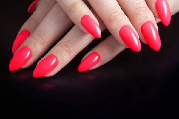 Manos de mujer con perfecta manicura roja. Esmalte de uñas color coral rojo. Fondo negro — Foto de Stock