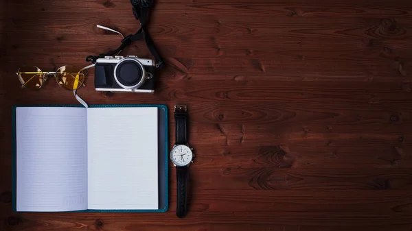 Planeando tu fin de semana. Plan de viaje. Diario, cámara y gafas de sol sobre el fondo de madera texturizada . — Foto de Stock