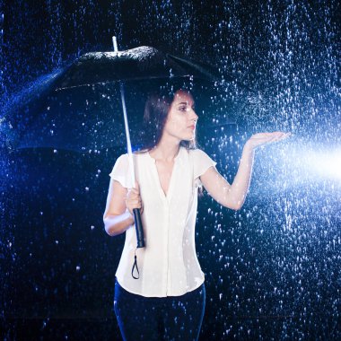 Kadın şemsiyesi altında. Yağmur damlaları dokunmak el uzatarak kız
