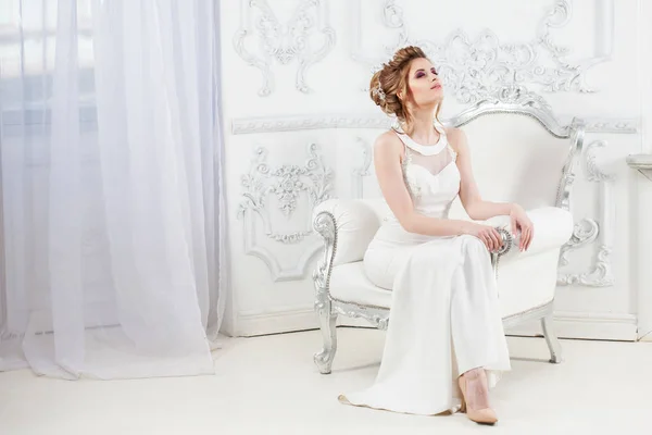 Ślub w stylu. Piękne młode panny młodej siedzi w krzesło luksus w luksusowym wnętrzu światła. — Zdjęcie stockowe