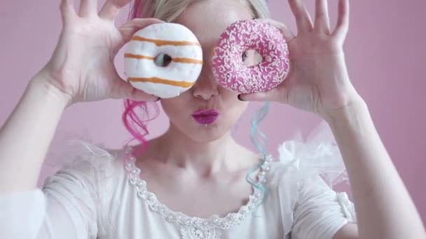 Grappige stijlvolle vrouw met gekleurd haar, spelen met donuts — Stockvideo