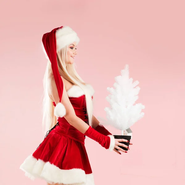 Charmante et séduisante femme blonde en costume de Père Noël avec arbre de Noël blanc . — Photo