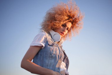 Sevimli Kıvırcık sarışın müzik aşığı. Büyük kulaklıklar ile genç kadın.