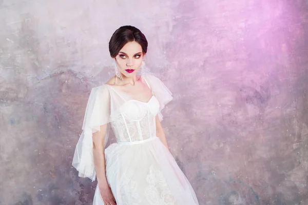 Красивая и стильная невеста в свадебном платье в студии на сером текстурированном фоне — стоковое фото