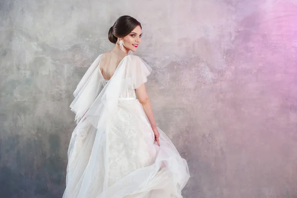 Szép és stílusos menyasszony, esküvői ruha stúdió, a szürke textúrázott háttérre — Stock Fotó