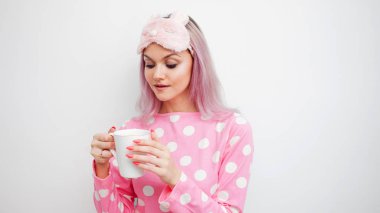 Mutlu genç kadın sabah kahve iç. Güzel kız pembe pijama ve sleepmask