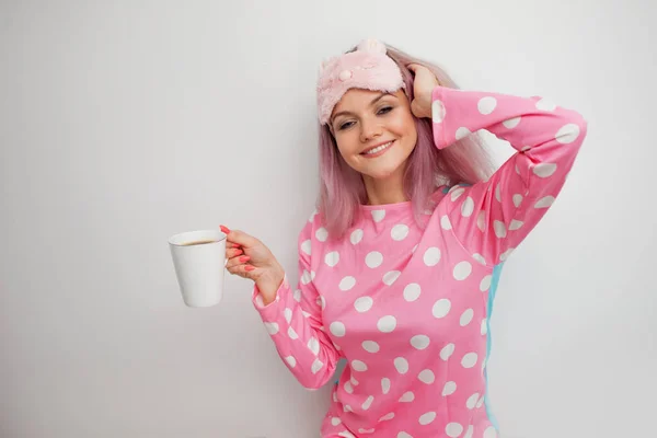 Щаслива молода жінка п'є ранкову каву. Красива дівчина в рожевій піжамі і сновидінні — стокове фото