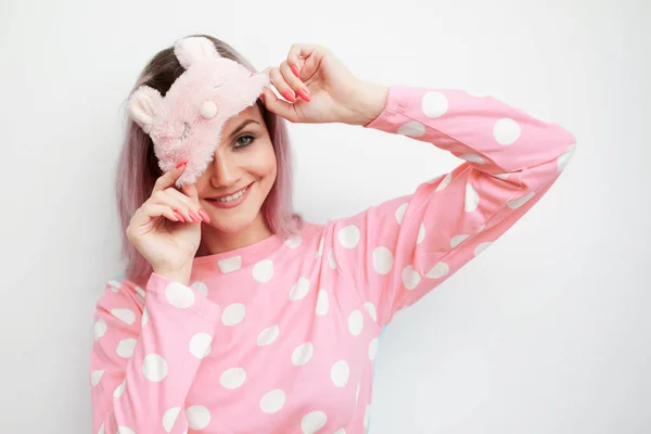 Linda jovem loira em pijama rosa e uma máscara de sono nos olhos — Fotografia de Stock