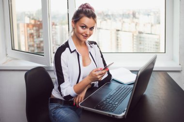 Genç sarışın bir dizüstü bilgisayarda çalışıyor. Modern ofisindeki kız