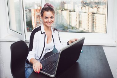 Genç sarışın bir dizüstü bilgisayarda çalışıyor. Modern ofisindeki kız