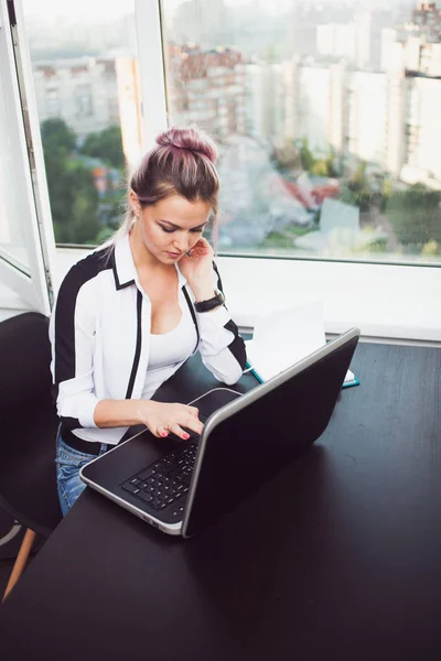Молода блондинка працює на ноутбуці. Дівчина в сучасному офісі — стокове фото