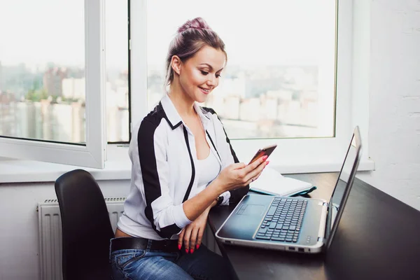 Fiatal nő ül egy laptop és egy okostelefon segítségével — Stock Fotó