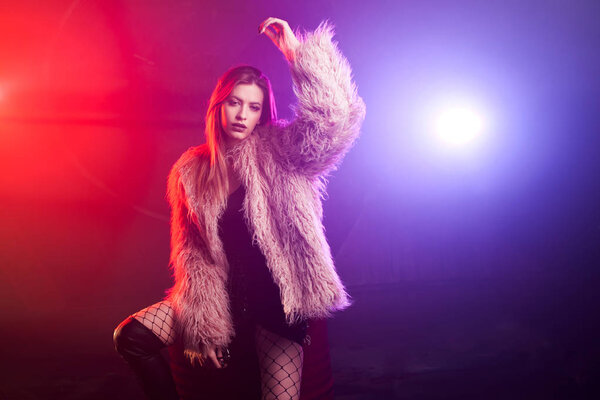 Модная девушка танцует в пушистом розовом пальто
