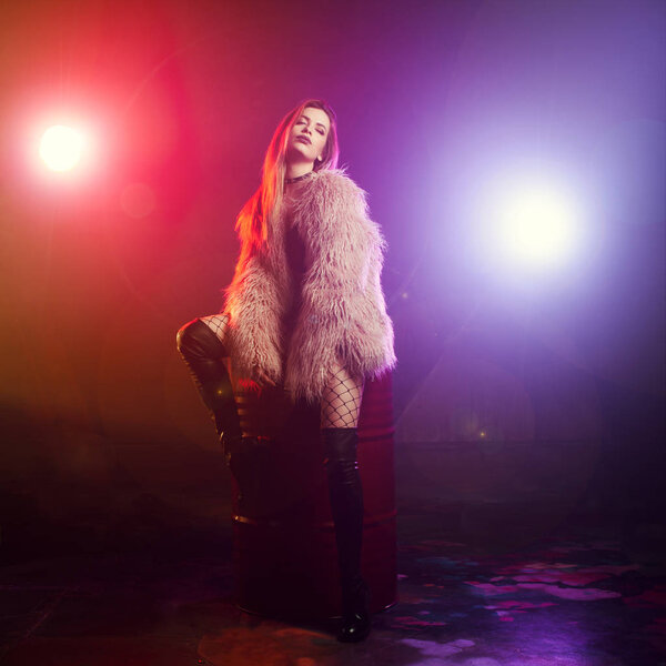 Модная девушка танцует в пушистом розовом пальто
