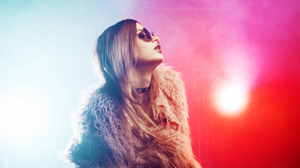 Модная девушка танцует в пушистом розовом пальто
