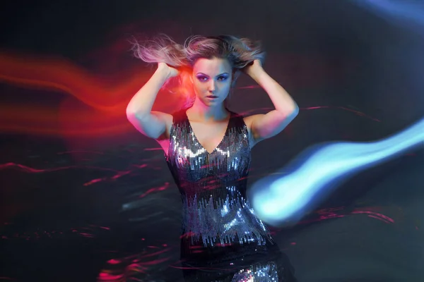 Kirkas ja tyylikäs nuori nainen tanssii klubilla, värivalo, liiketehosteet — kuvapankkivalokuva