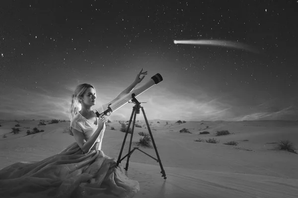 Mujer joven sueña, concepto. Chica mira a un cometa o estrella que cae utiliza un telescopio. Fondo del desierto , — Foto de Stock