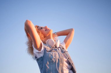 Gökyüzü arka plan üzerinde büyük kulaklıklar, sağdaki boş alan ile trendy kız.