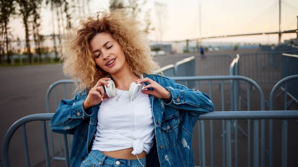 Schöne und fröhliche junge Frau mit üppigem Haar, im Freien. Charmante lockige Haare in Jeansjacke. — Stockfoto