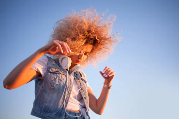 Fille à la mode avec de grands écouteurs sur fond de ciel, espace libre sur la droite . — Photo