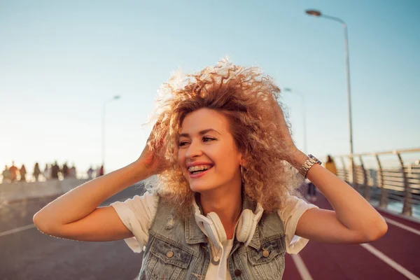 Una joven feliz en la calle. Hermosa rubia con auriculares y smartphone . —  Fotos de Stock