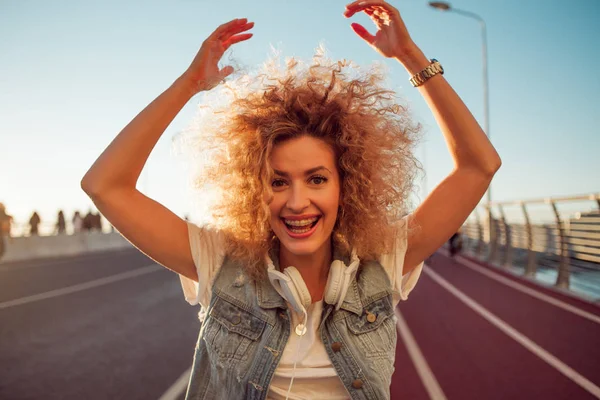 Sokaktaki mutlu genç kız. Akıllı telefon ve kulaklık ile güzel sarışın.