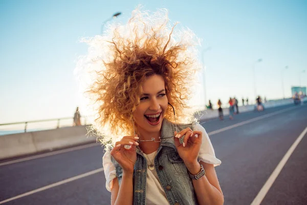 Красивая и веселая молодая женщина с пышными волосами, на открытом воздухе — стоковое фото