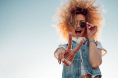 Gür saçlı genç şık kadın göstermek zafer işareti